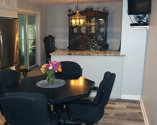 Dining room with a round black table, dark chairs, flowers, and a china cabinet near a sliding glass door In Bucks County PA