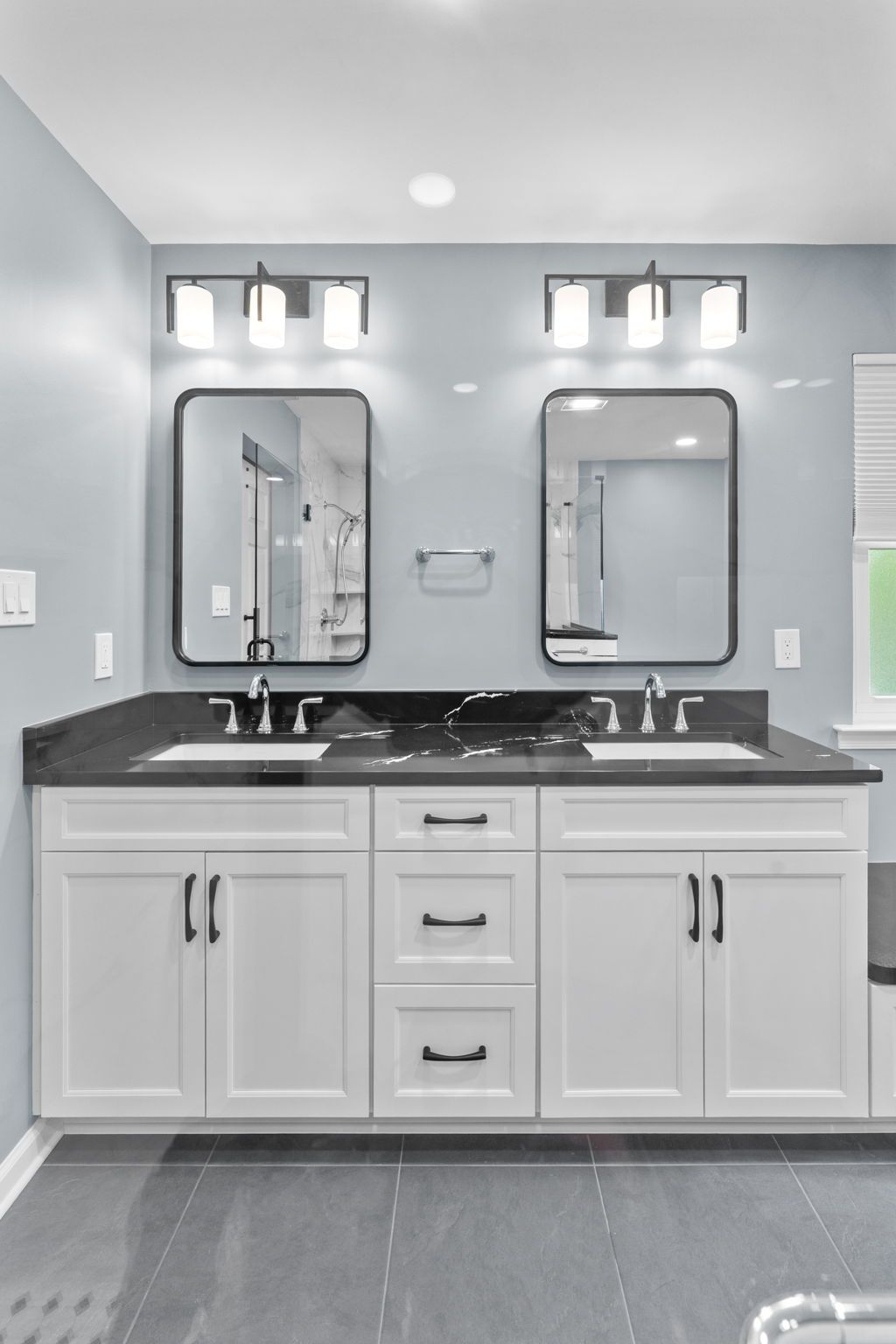 Modern bathroom vanity with double sinks, mirrors, and wall lights in a gray and white interior In Bucks County PA