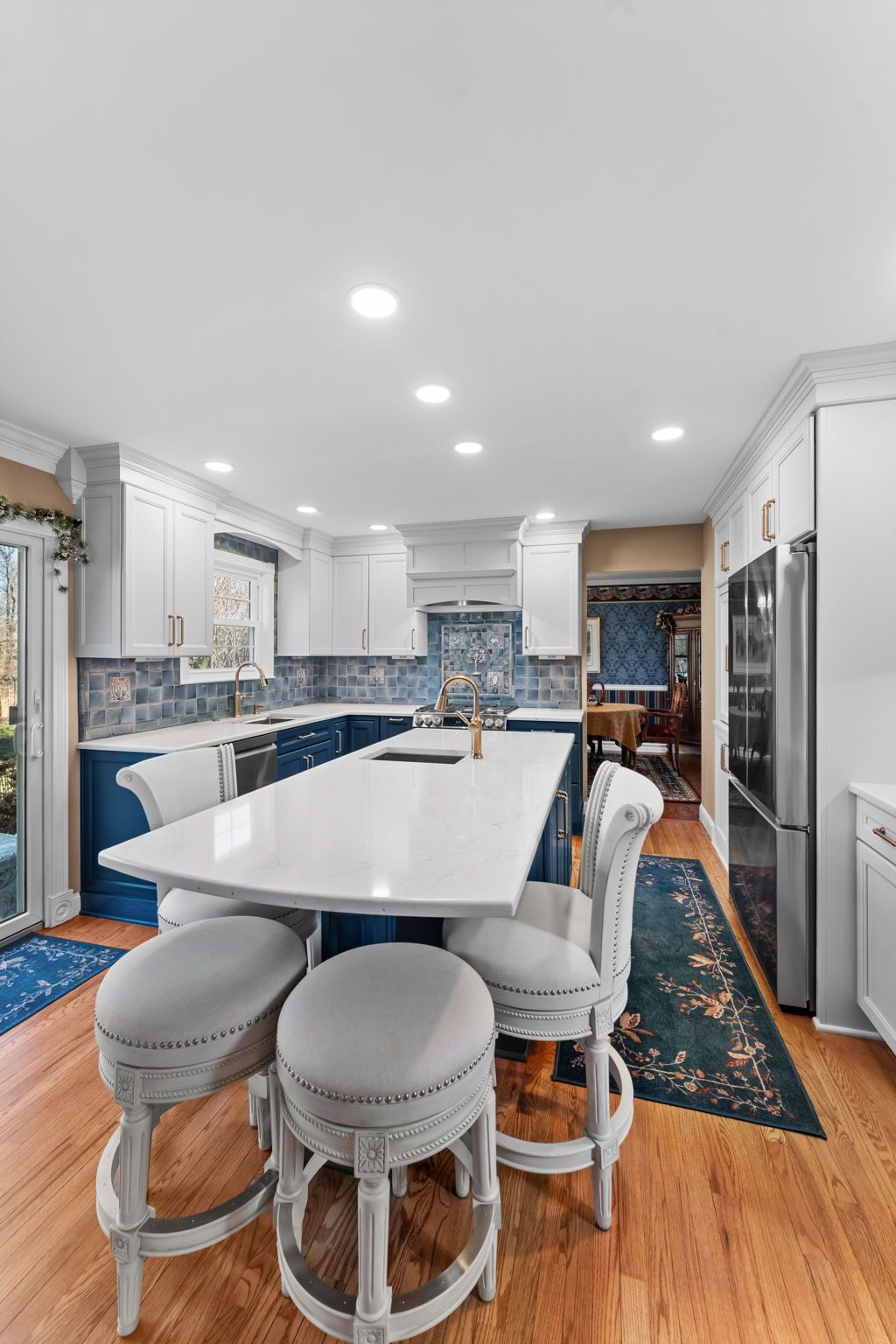 Bright modern kitchen with white island, blue cabinets, stools, and hardwood floors  In Bucks County PA