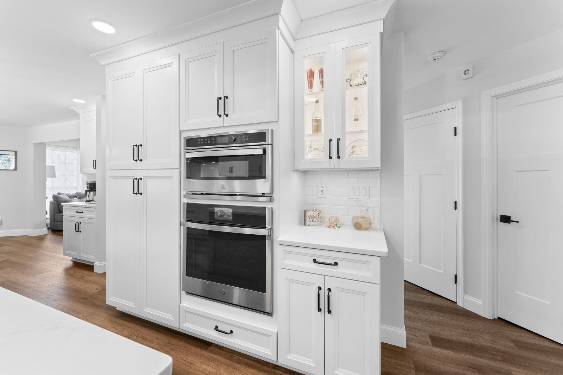 Bright white kitchen with built-in double ovens, tall cabinets, and wood floors In Bucks County PA