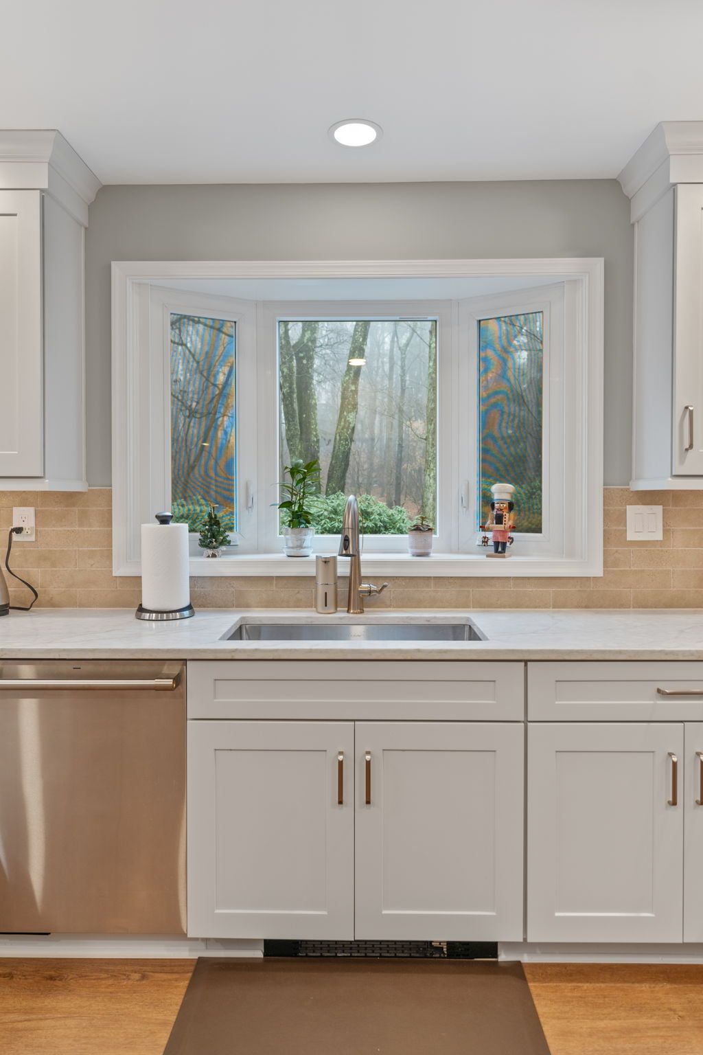 Bright kitchen with a large window over a sink, white cabinets, and stainless steel dishwasher In Bucks County PA