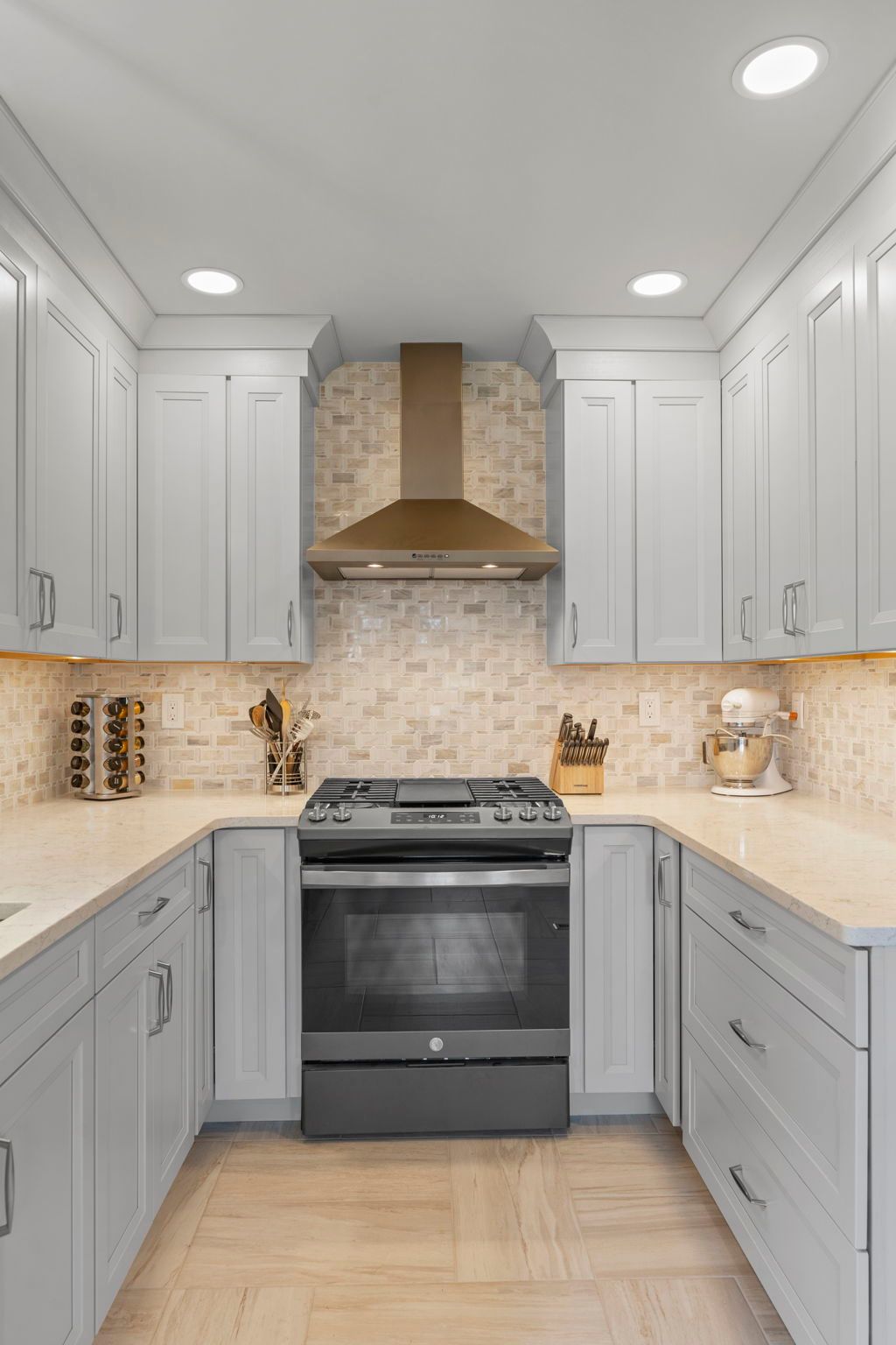 Modern kitchen with gray cabinets, black stove, white countertops, and stone backsplash In Bucks County PA