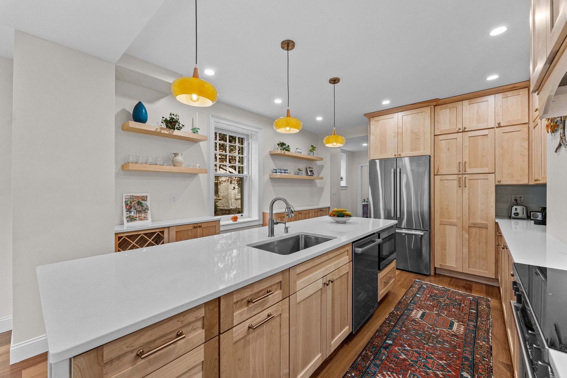 Modern kitchen with wood cabinets, white island, stainless fridge, and yellow pendant lights In Bucks Country PA