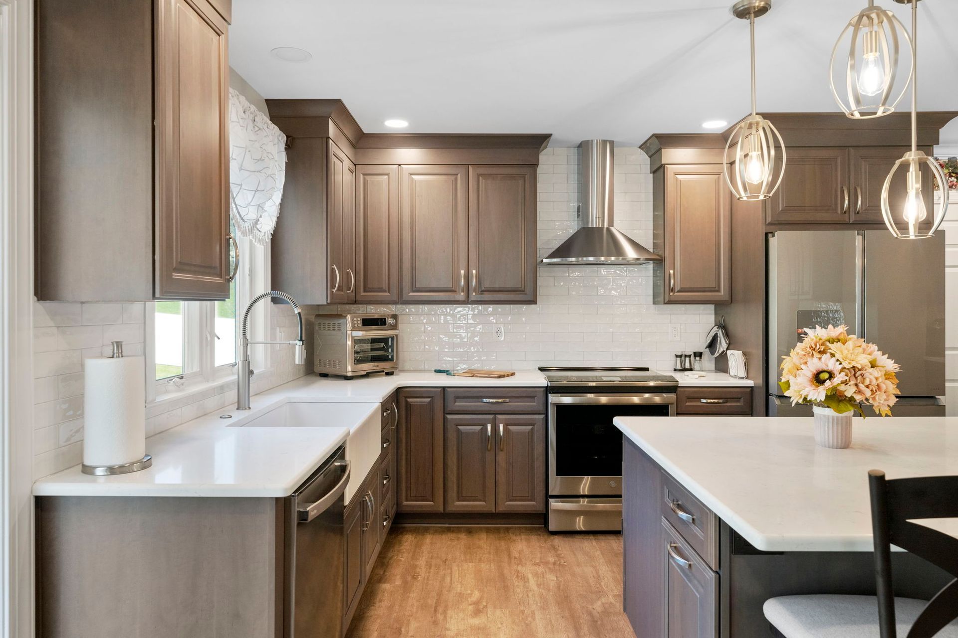 Modern kitchen with brown cabinets, white countertops, stainless appliances, and a central island with flowers In Bucks Country PA