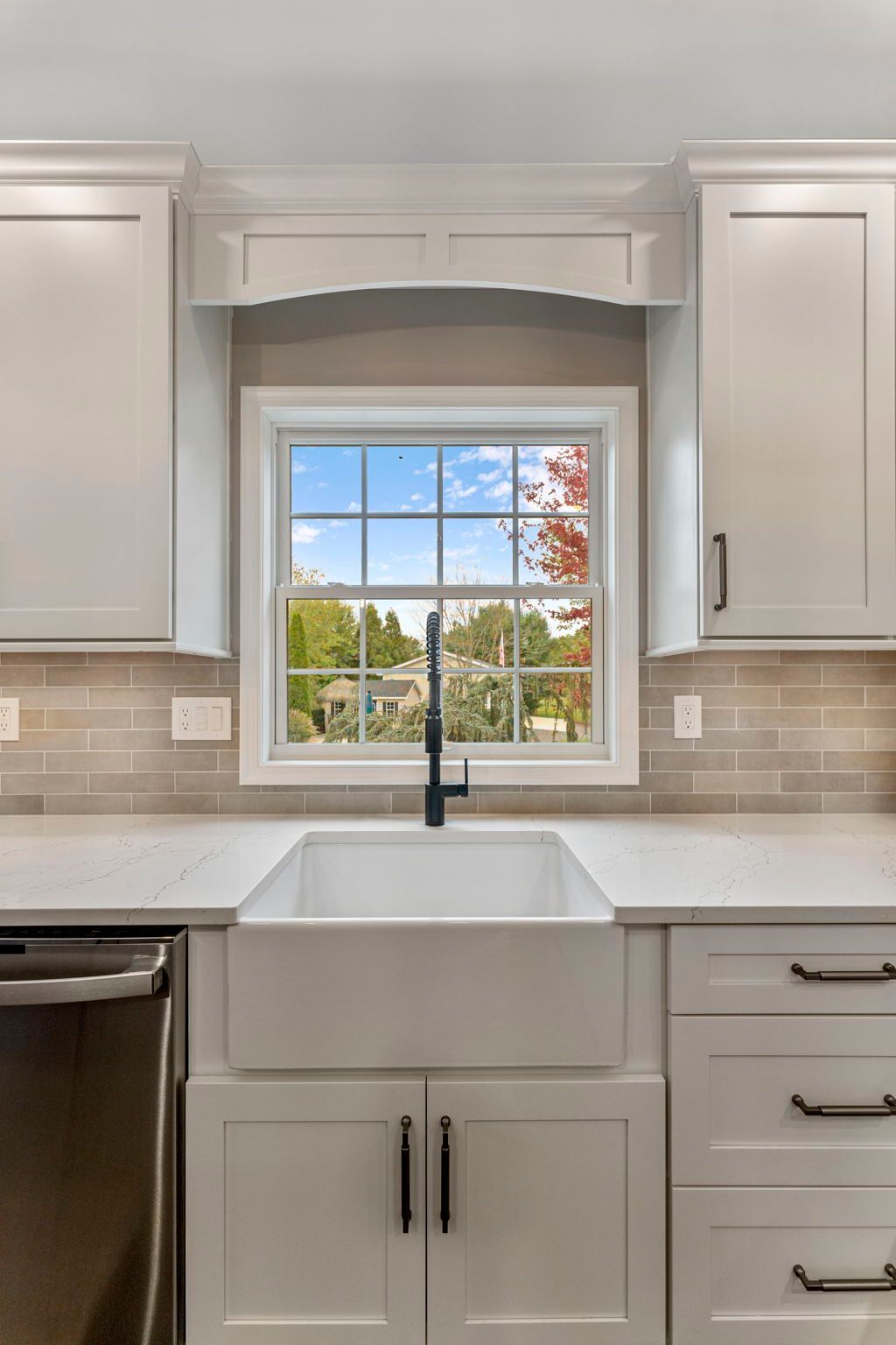 Modern white kitchen with farmhouse sink under a window and light gray cabinets  In Bucks County PA
