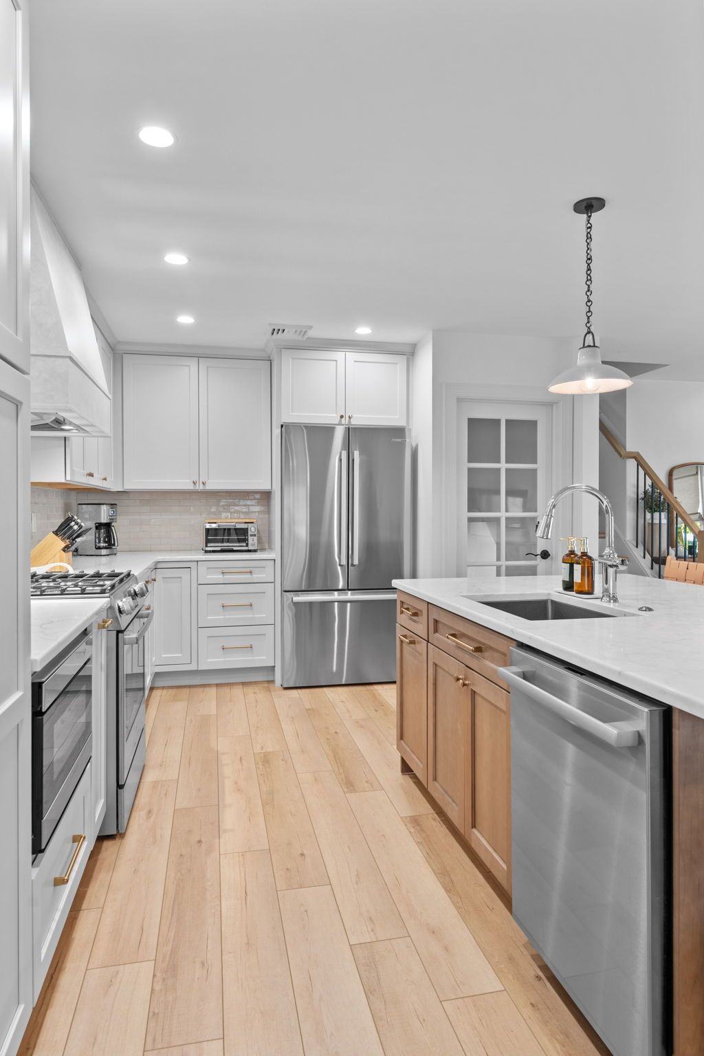 Bright modern kitchen with stainless steel appliances, white cabinets, and light wood flooring In Bucks County PA