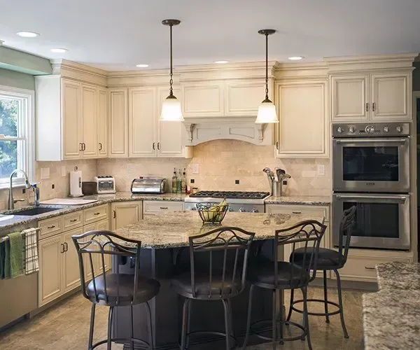 Bright cream kitchen with island, pendant lights, stainless appliances, and barstools In Bucks Country PA
