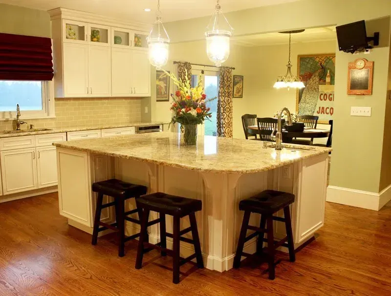 Bright kitchen with a large island, wooden stools, white cabinets, and warm hardwood floors In Bucks County PA