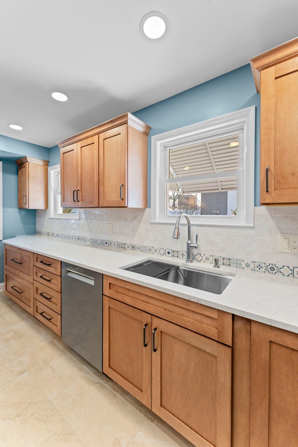 Bright kitchen with light wood cabinets, speckled countertops, stainless dishwasher, and a window over the sink In Bucks County PA