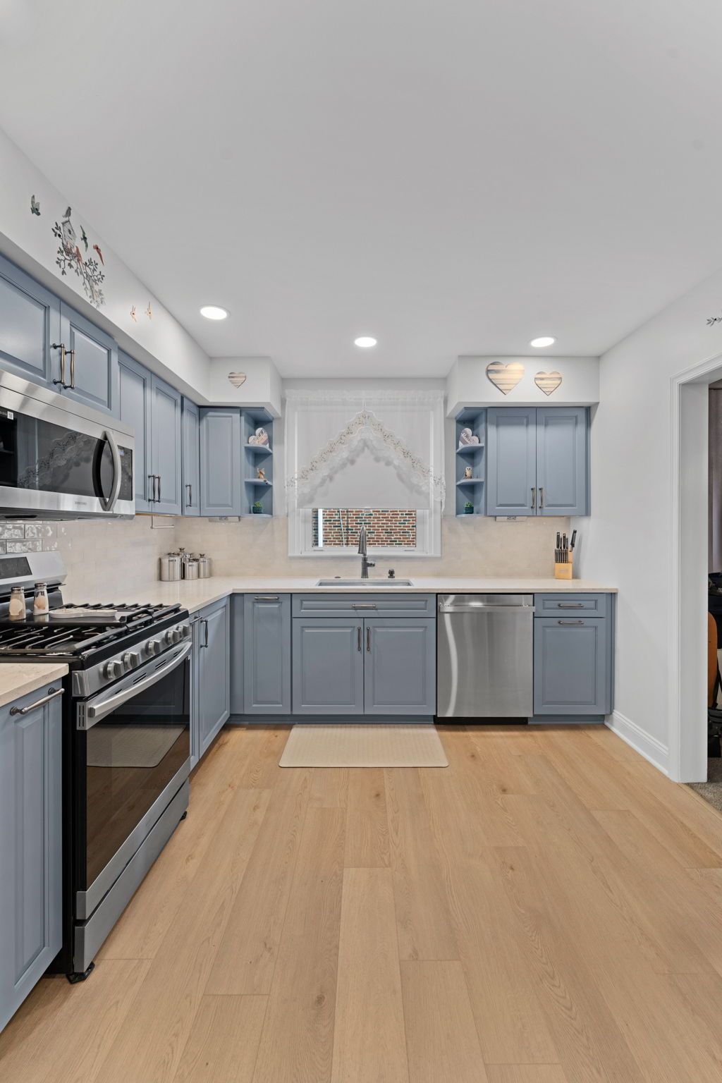 Modern kitchen with gray cabinets, stainless appliances, white backsplash, and light wood flooring In Bucks County PA