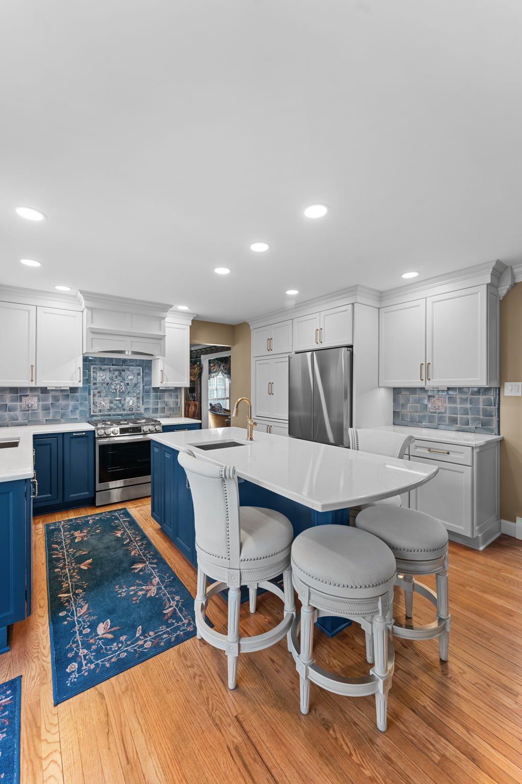 Bright modern kitchen with white cabinets, blue tile backsplash, island, and wooden floor In Bucks Country PA