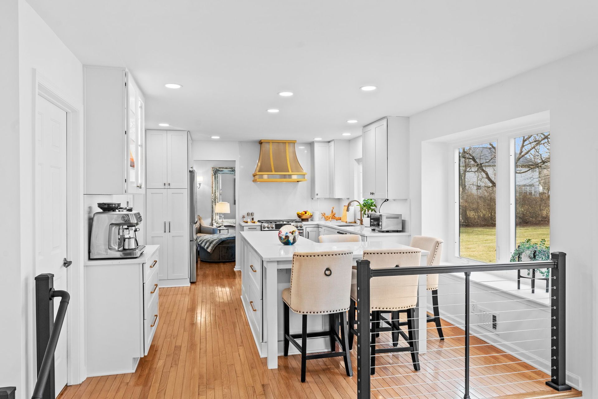 Bright modern kitchen with white cabinets, island seating, and large windows overlooking a backyard In Bucks Country PA