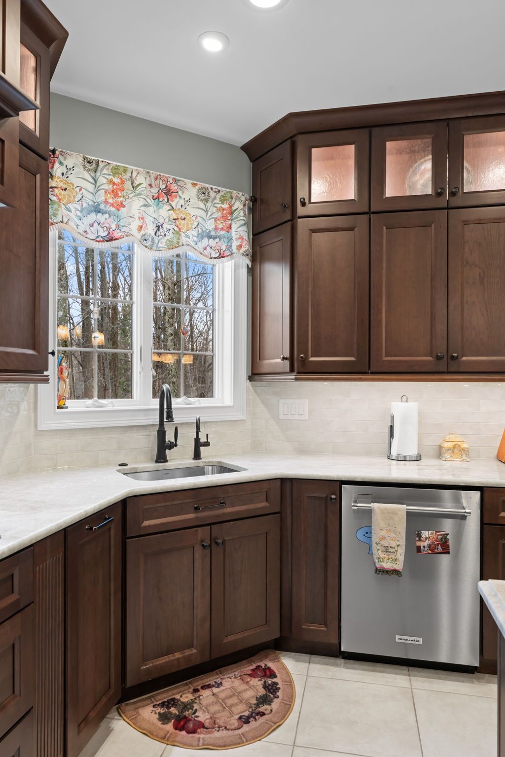 Kitchen corner with dark wood cabinets, white countertops, a window, and a stainless dishwasher In Bucks Country PA