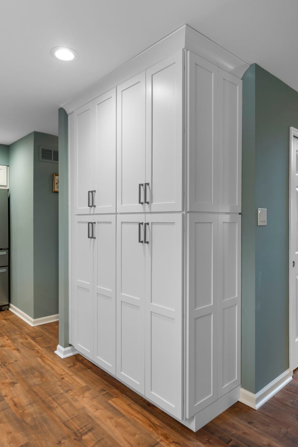 White built-in hallway cabinets against sage green walls in a wood-floored home interior In Bucks Country PA