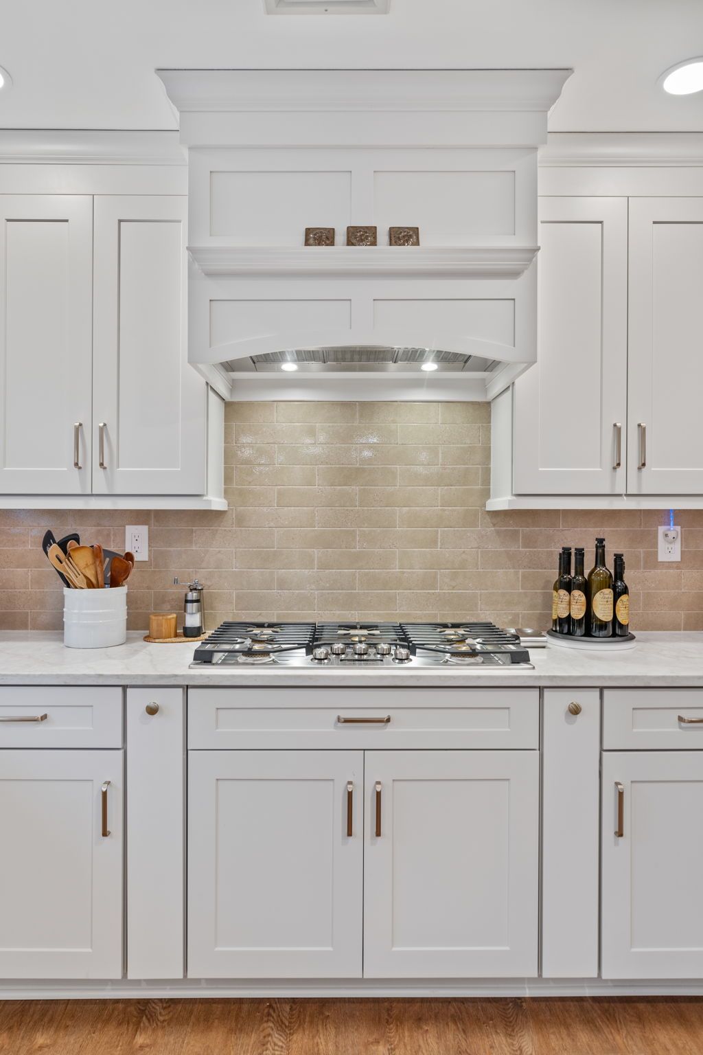 Bright white kitchen with cabinets, gas stove, beige tile backsplash, and countertop decor In Bucks County PA