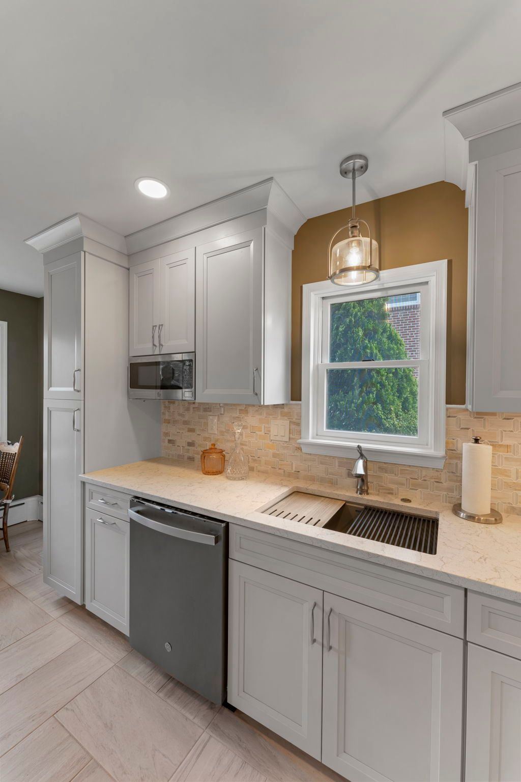 Bright kitchen with gray cabinets, white countertops, pendant light, and a window above the sink In Bucks County PA
