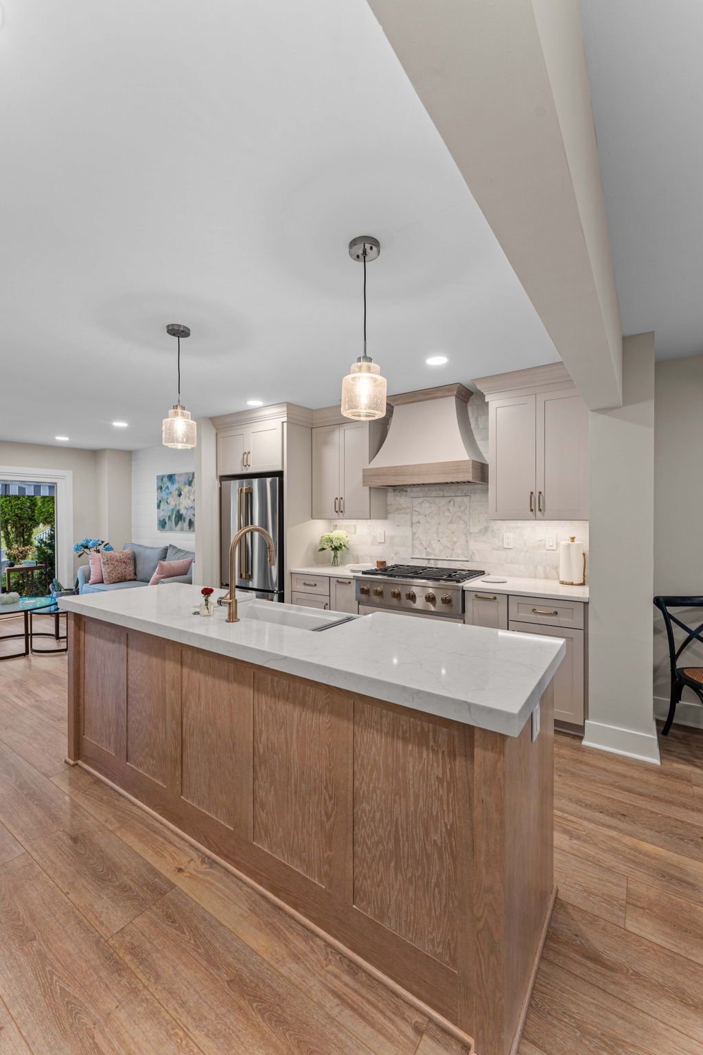 Modern kitchen with large island, pendant lights, stainless range hood, and wood floors In Bucks Country PA