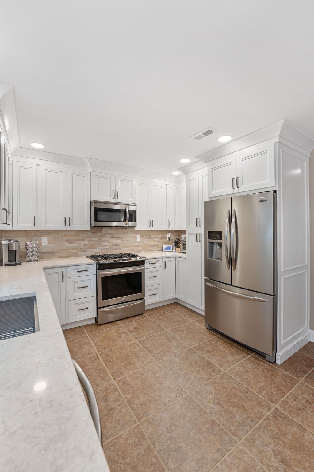 Bright white modern kitchen with stainless steel appliances and tan tile floor In Bucks County PA