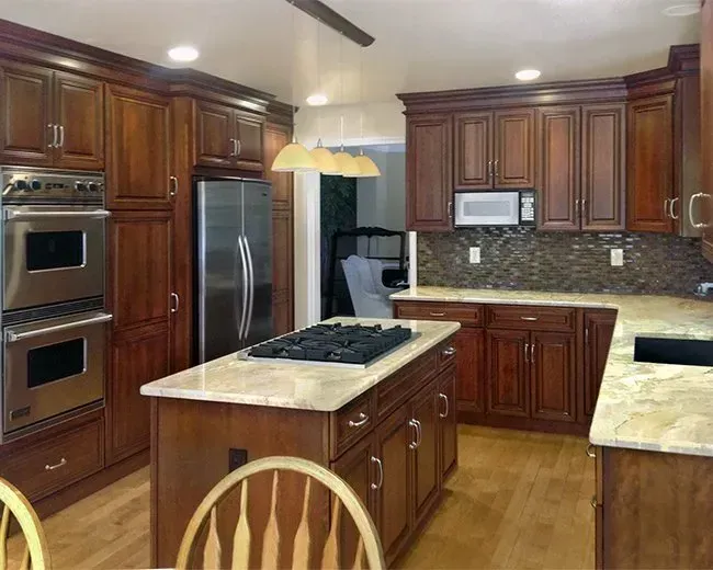 Modern kitchen with dark wood cabinets, stainless steel appliances, and a marble island countertop In Bucks County PA