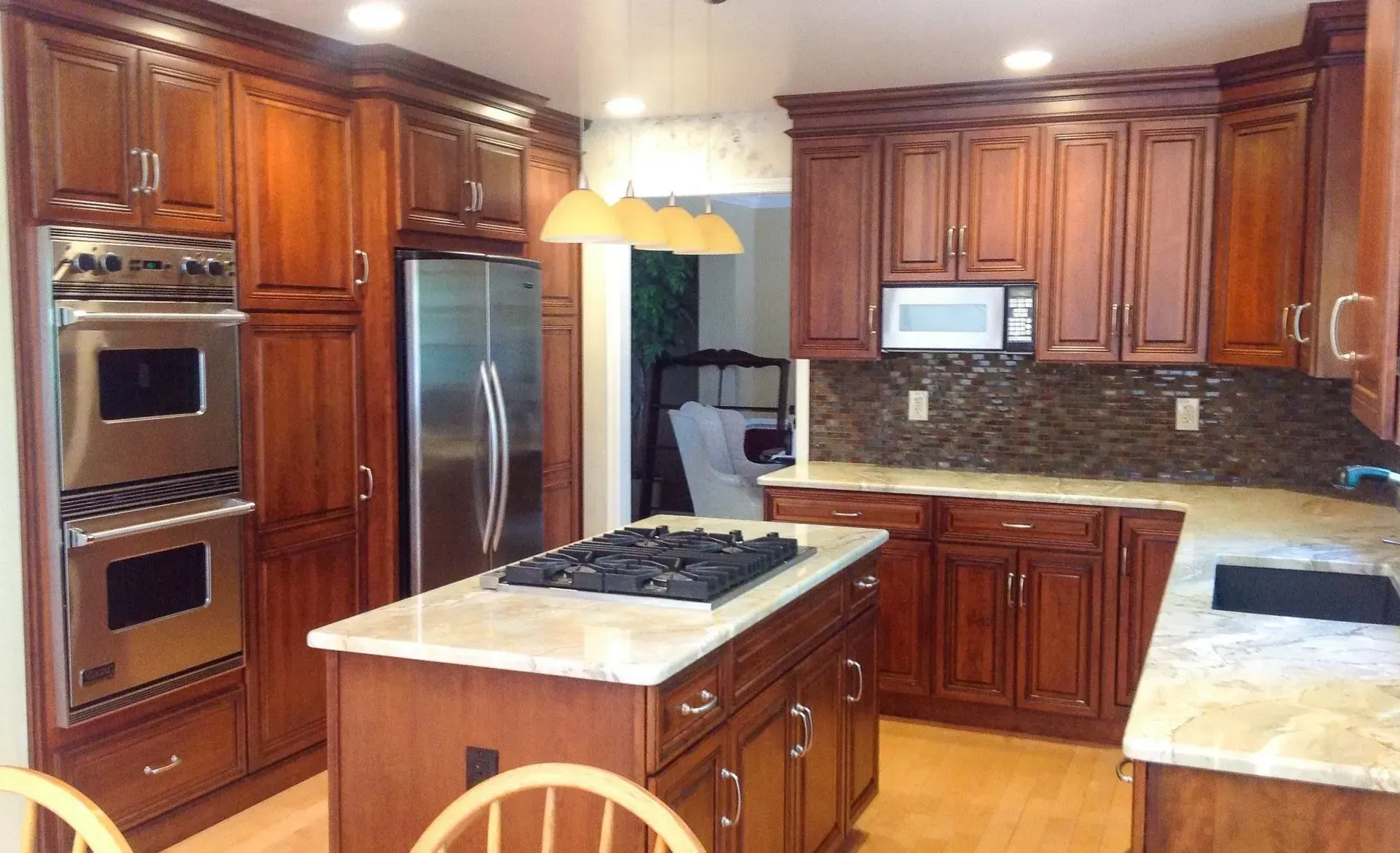 Modern kitchen with cherry wood cabinets, stainless steel appliances, and a central island under pendant lights In Bucks County PA