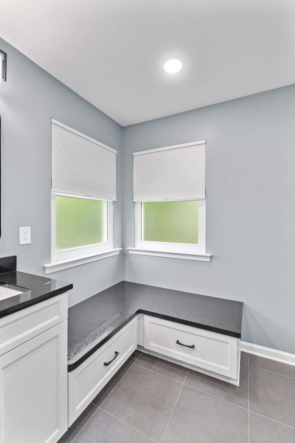 Corner kitchen nook with gray walls, white blinds, built-in bench, and gray tile floor In Bucks County PA