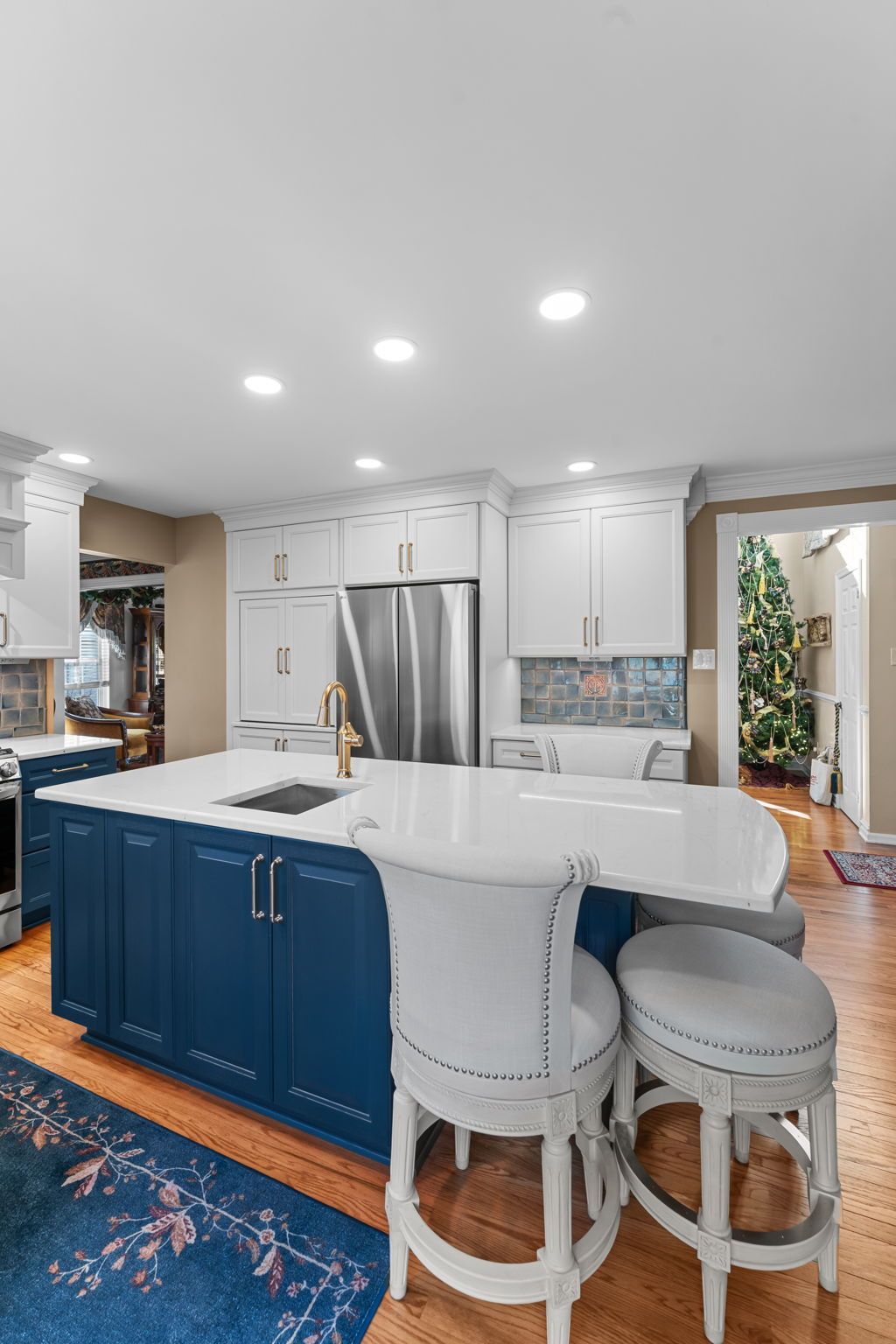 Bright kitchen with blue island, white cabinets, bar stools, and warm wood floors  In Bucks County PA
