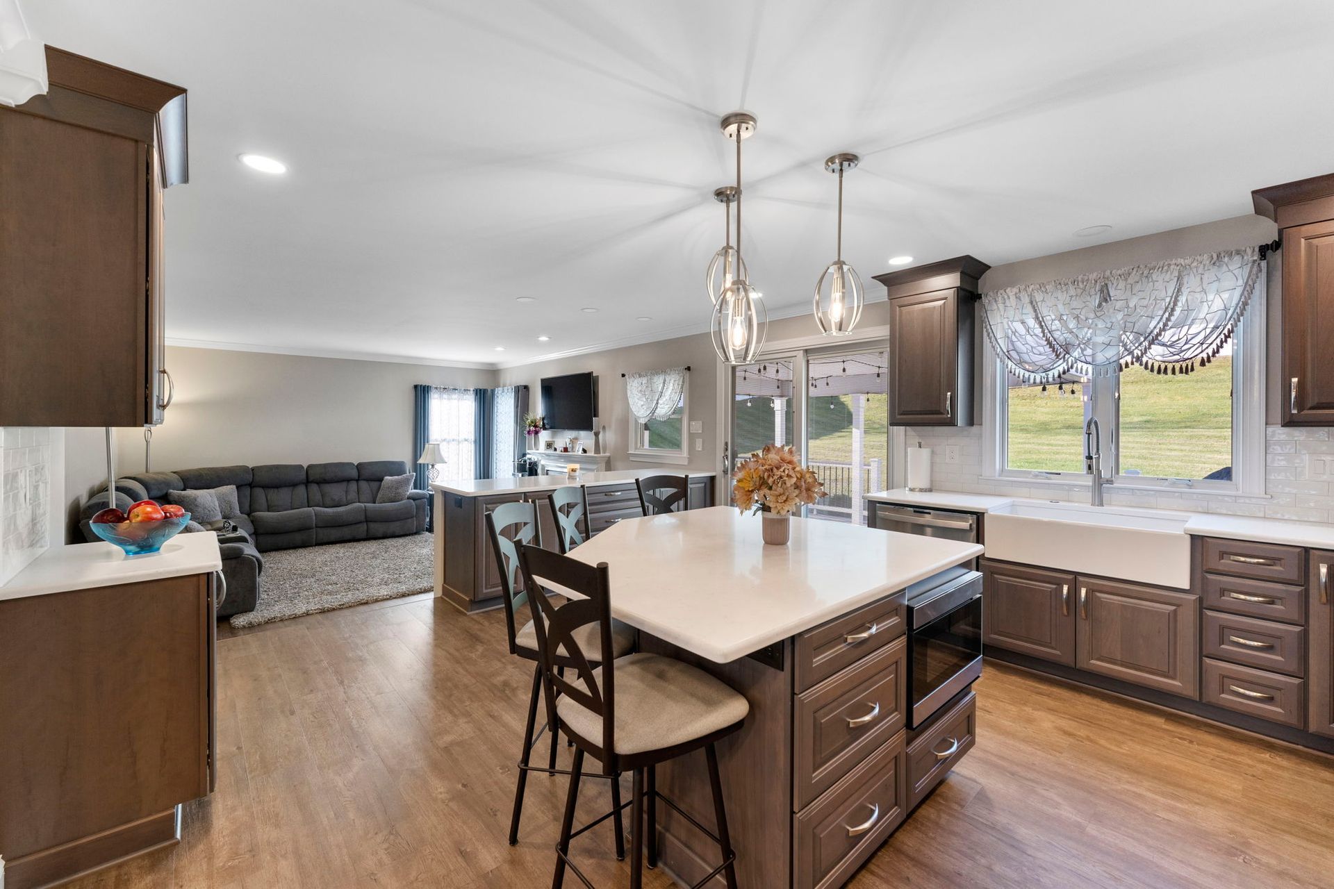 Open-concept kitchen and living room with white island, wood cabinets, and large windows In Bucks Country PA