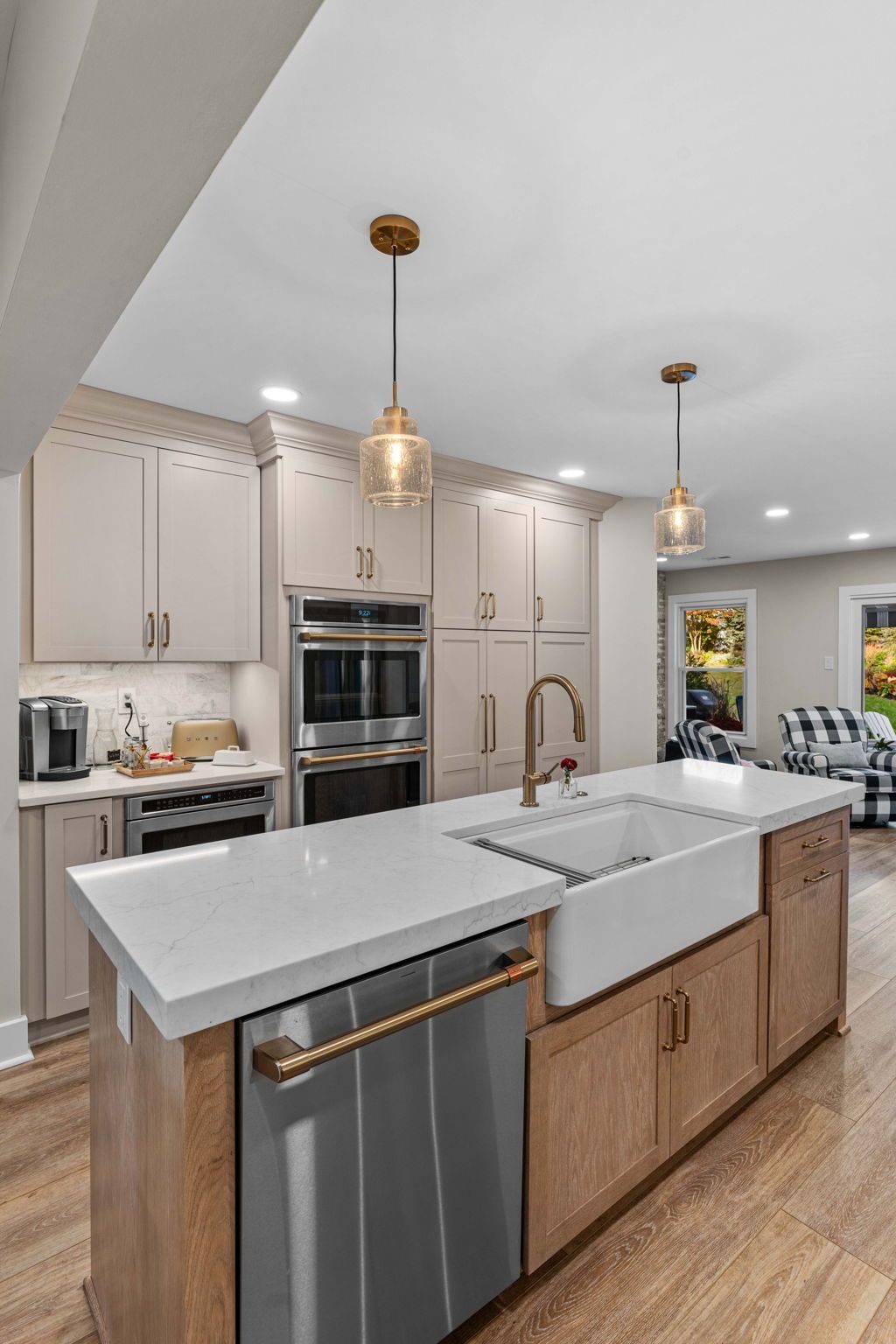 Modern kitchen with white cabinets, marble island, gold pendant lights, and stainless appliances in Bucks County PA