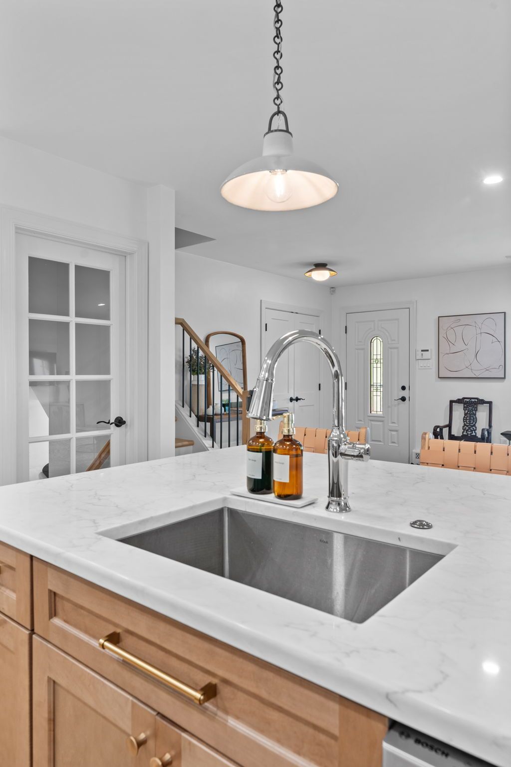Bright modern kitchen with white marble island, double sink, brass faucet, and wood cabinets In Bucks County PA