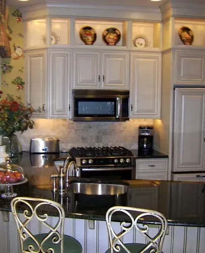 Bright kitchen with white cabinets, black granite island, stainless stove, and decorative plates above the cabinets In Bucks County PA