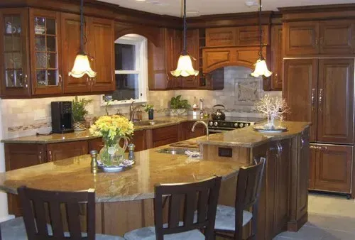 Spacious kitchen with dark wood cabinets, granite island, and three pendant lights over a dining table in Bucks County PA