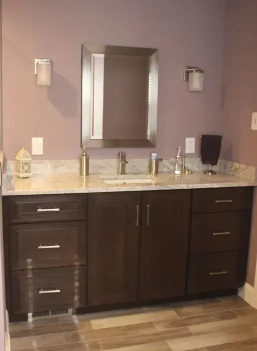 Bathroom vanity with dark wood cabinets, light countertop, and wall-mounted mirror between two sconces in Bucks Country PA