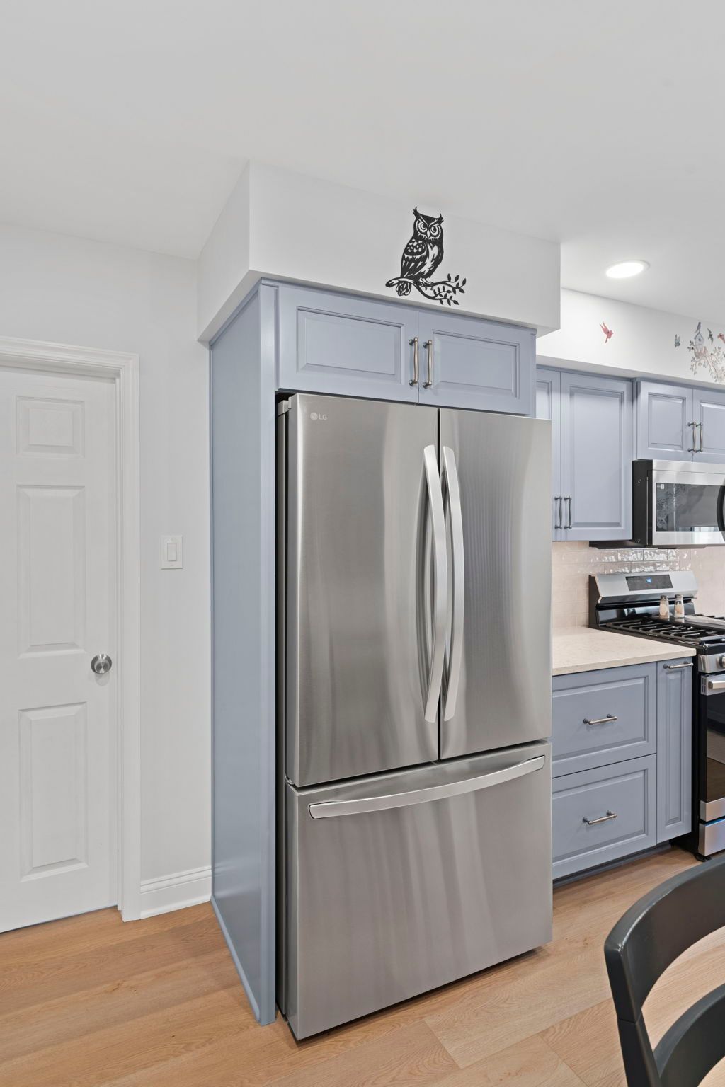 Stainless steel refrigerator in a bright kitchen with light blue cabinets and a wood floor In Bucks County PA