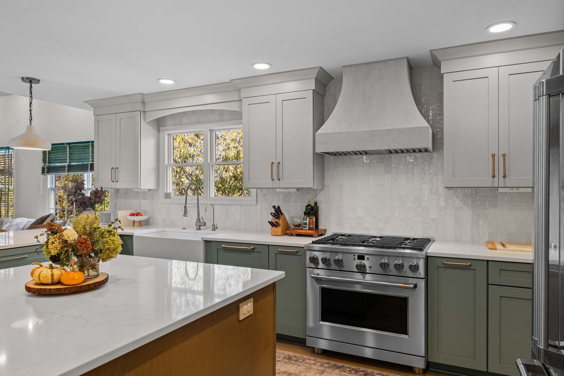 Modern kitchen with white cabinets, marble counters, stainless stove, and a fruit bowl on the island in Bucks County PA