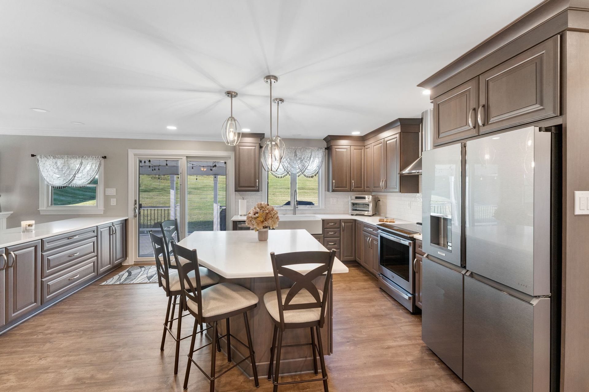 Modern kitchen with island, wood floors, stainless steel appliances, and large windows In Bucks Country PA