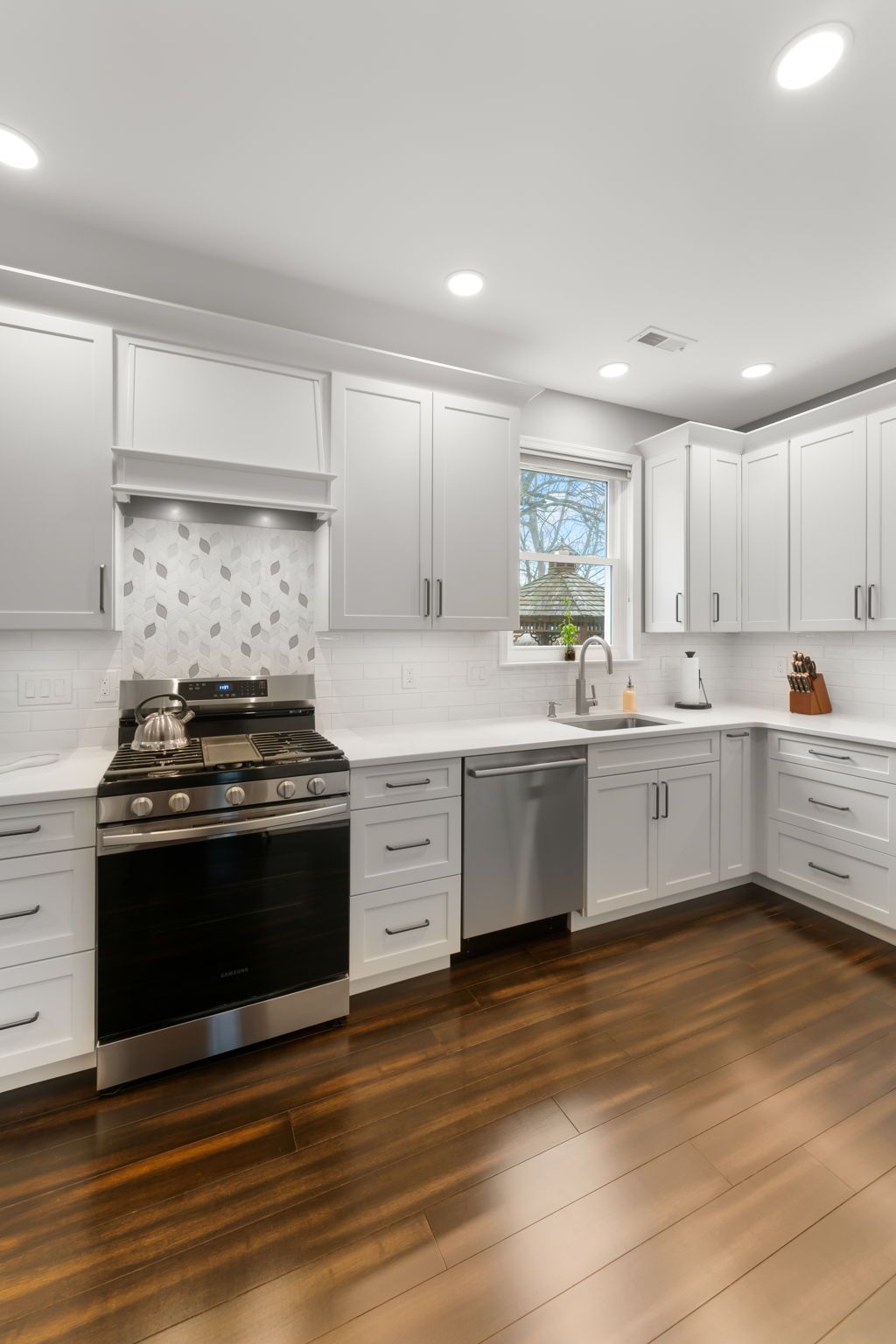 Bright modern kitchen with white cabinets, stainless appliances, and dark hardwood floors  In Bucks County PA