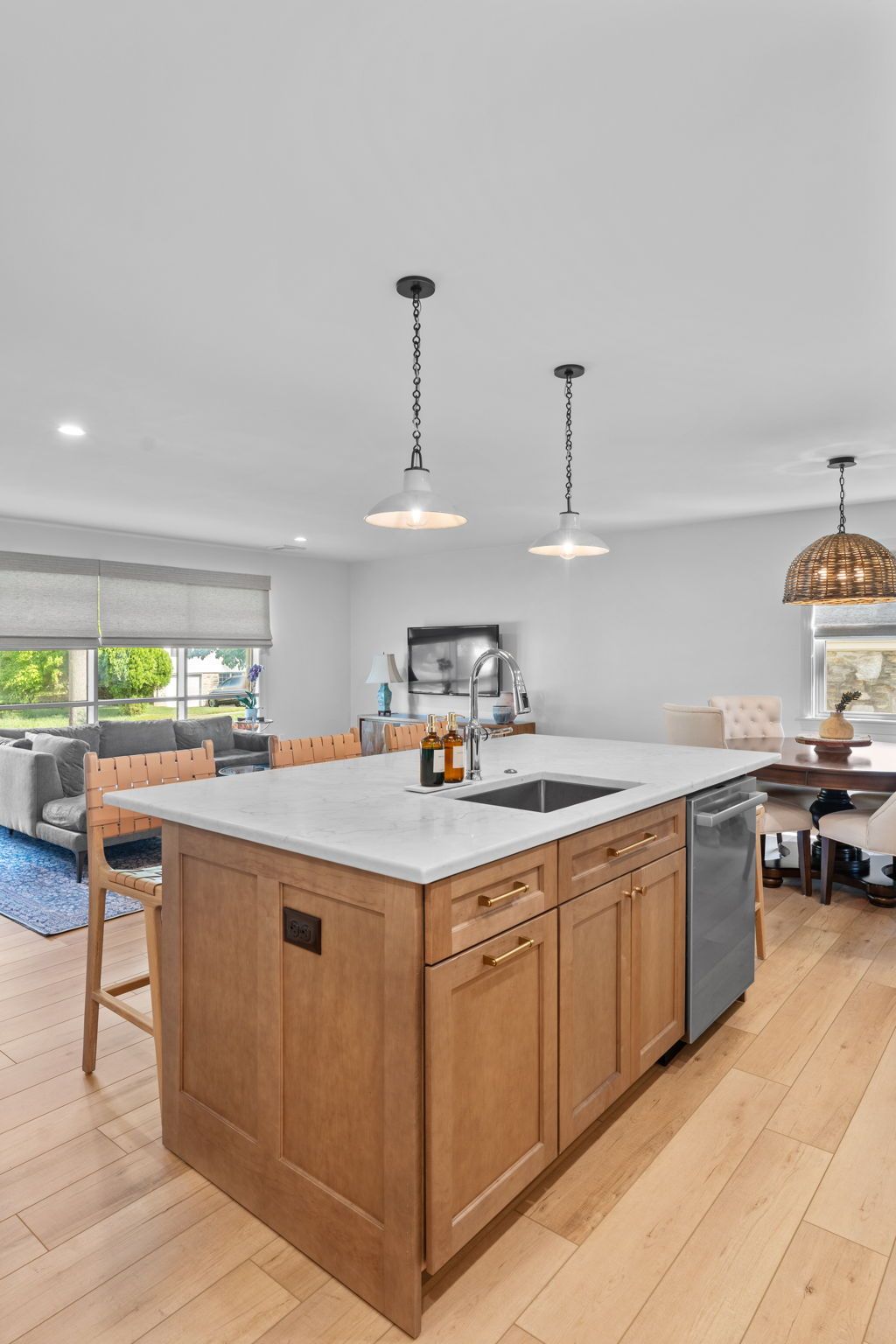 Bright open kitchen with a large wooden island, white countertops, and hanging pendant lights In Bucks County PA