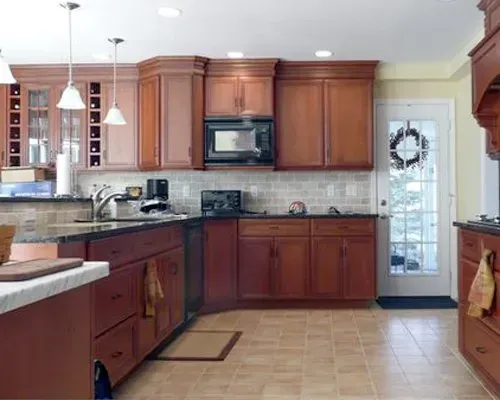 Modern kitchen with cherry cabinets, black countertops, tile floor, and a glass door with wreath  In Bucks County PA