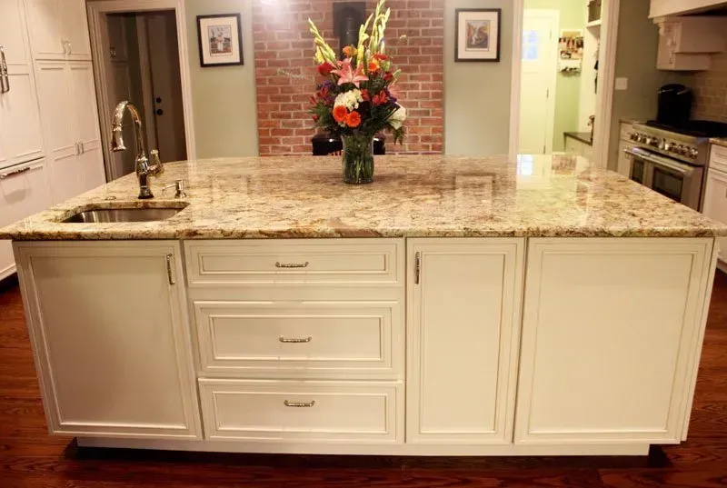 Large cream kitchen island with granite countertop and flower vase in a bright kitchen In Bucks County PA