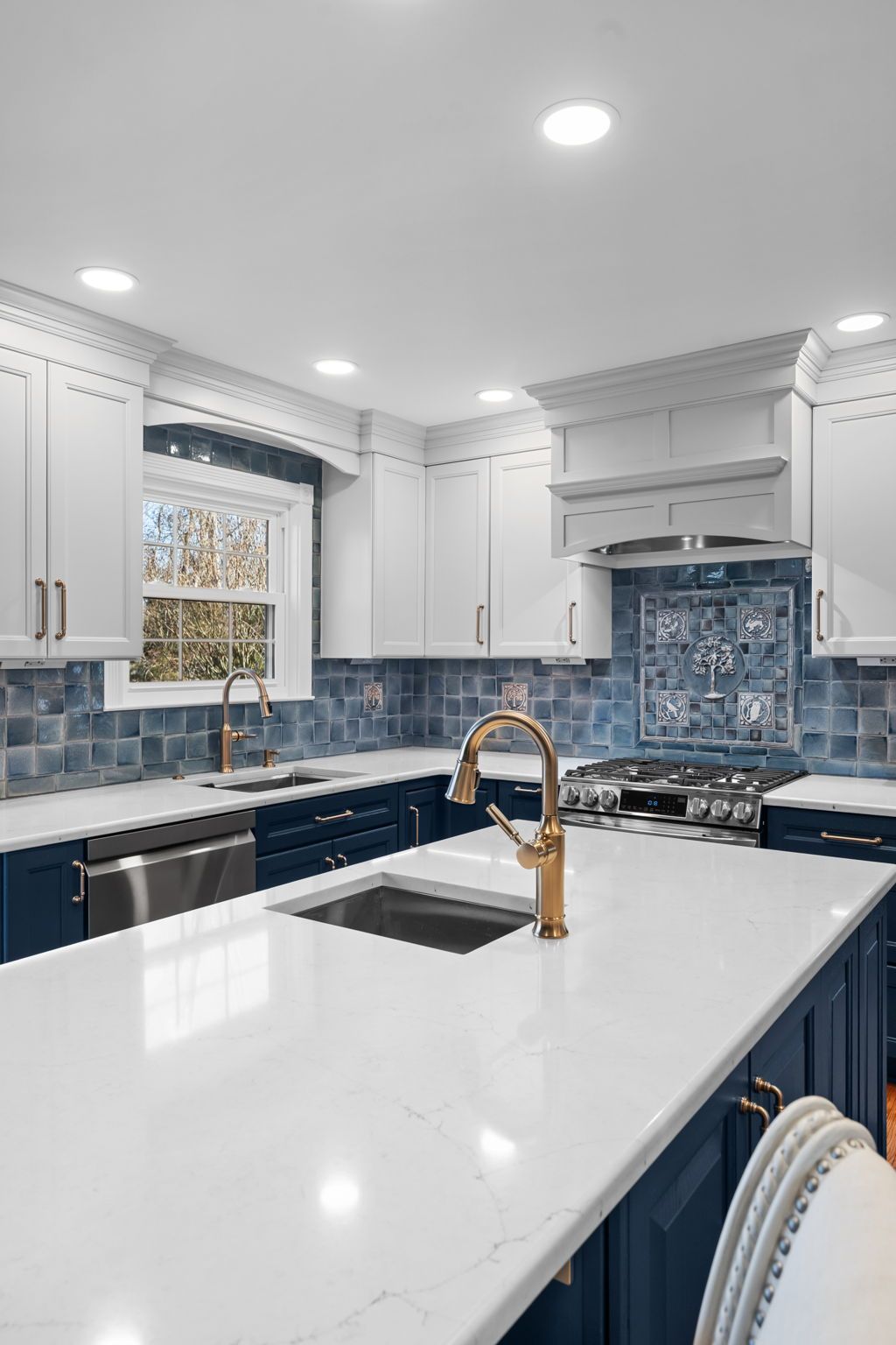 Modern white kitchen with navy cabinets, marble island, gold faucet, and blue tile backsplash  In Bucks County PA