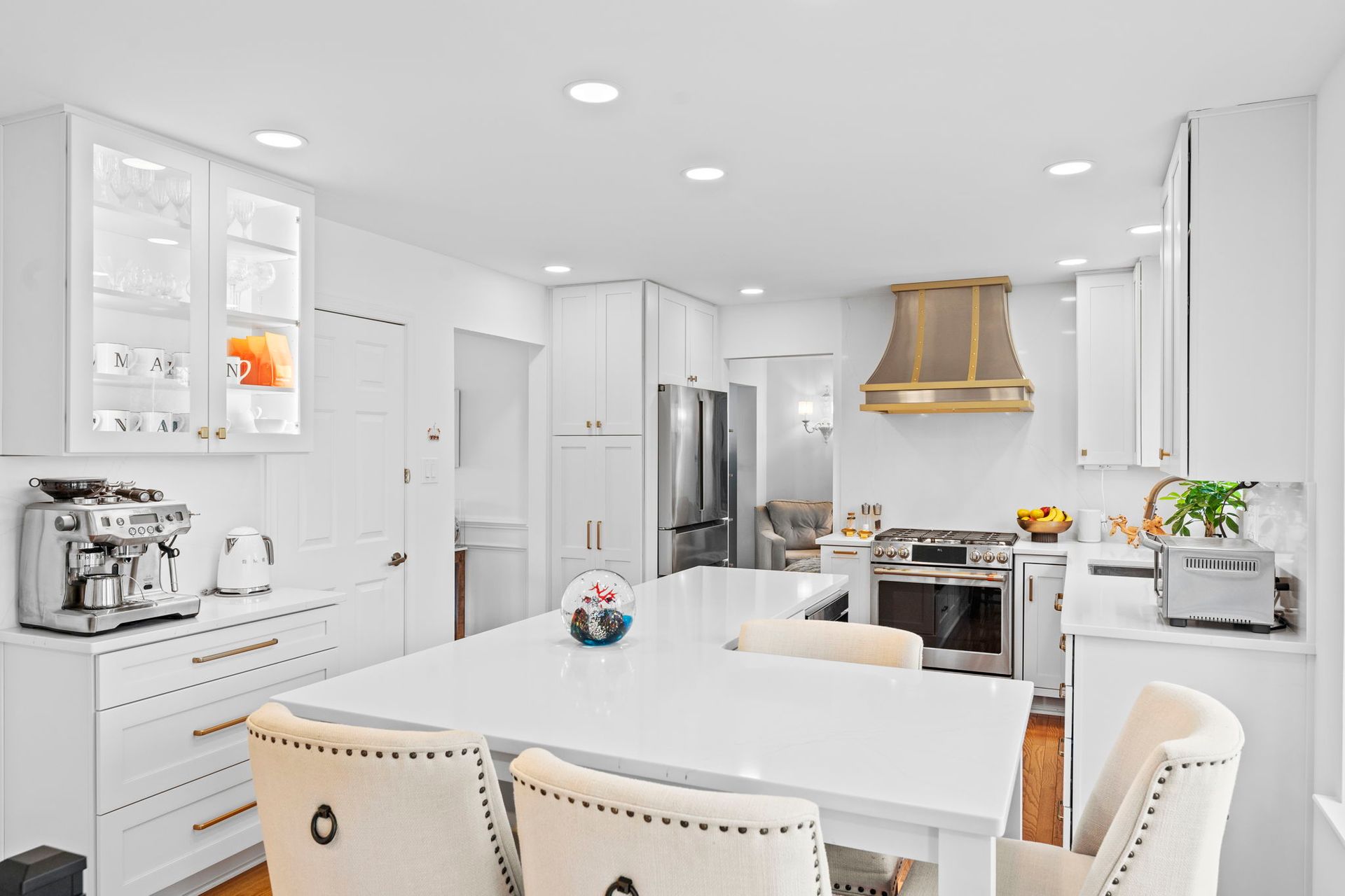 Bright white modern kitchen with island, stainless steel appliances, and gold range hood In Bucks Country PA