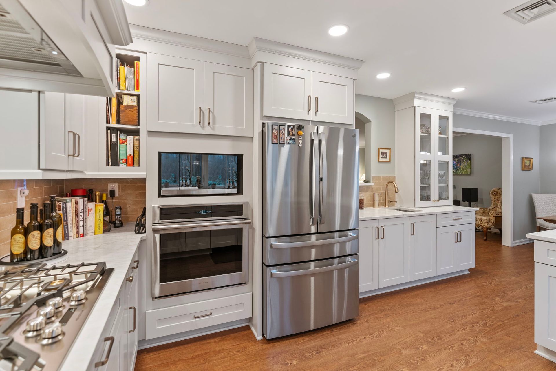 Modern white kitchen with stainless steel appliances, island cooktop, and hardwood floor In Bucks County PA