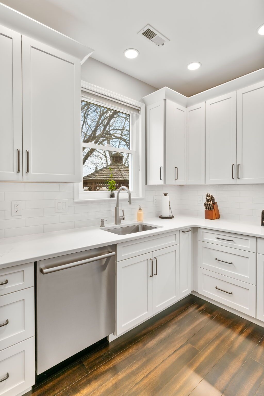 Bright white kitchen with stainless dishwasher, corner sink, and wood floors, seen in daylight  In Bucks County PA