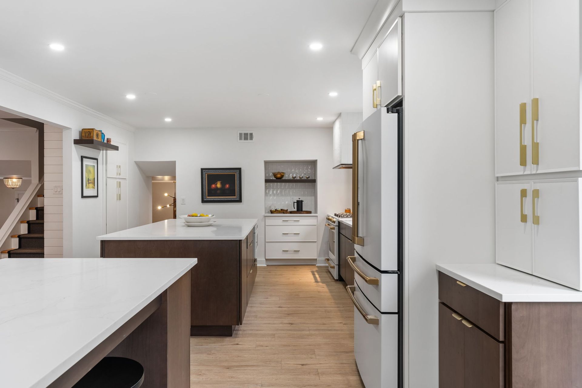 Bright modern kitchen with white cabinets, island, stainless appliances, and wood floors