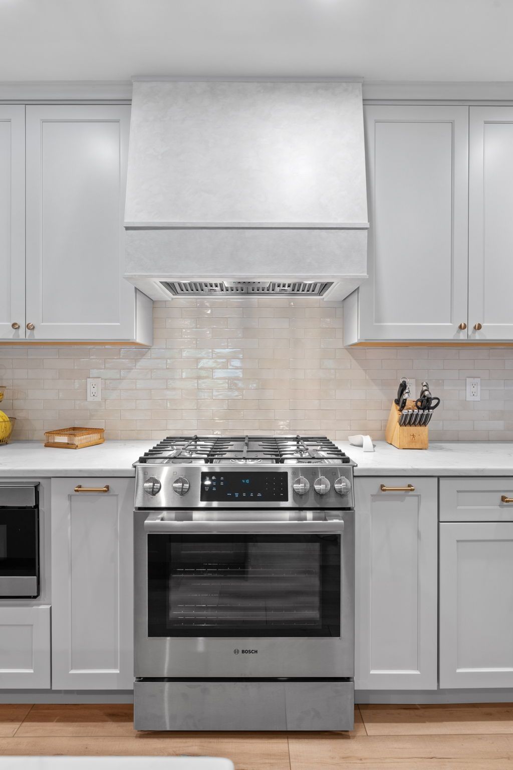 Modern kitchen with stainless steel stove, white cabinets, gray countertops, and tile backsplash In Bucks County PA