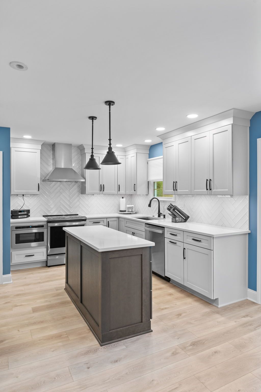 Bright modern kitchen with white cabinets, gray island, stainless appliances, and pendant lights in Bucks County PA