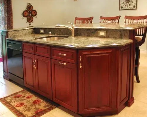 Cherry wood kitchen island with granite countertop and built-in sink in a warm dining area  In Bucks County PA