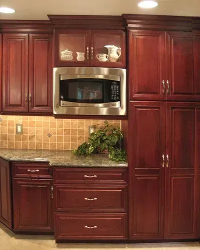 Cherry wood kitchen cabinets with stainless microwave, tan tile backsplash, and granite countertop  In Bucks County PA