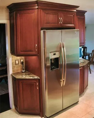 Stainless steel refrigerator built into dark wood kitchen cabinetry beside a granite counter  In Bucks County PA