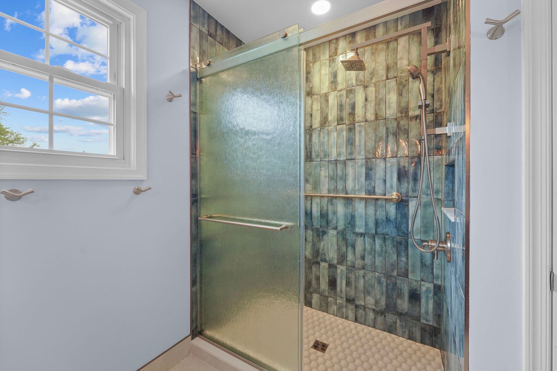 Bathroom with frosted glass shower door, mosaic tile wall, and a window with white trim  In Bucks County PA